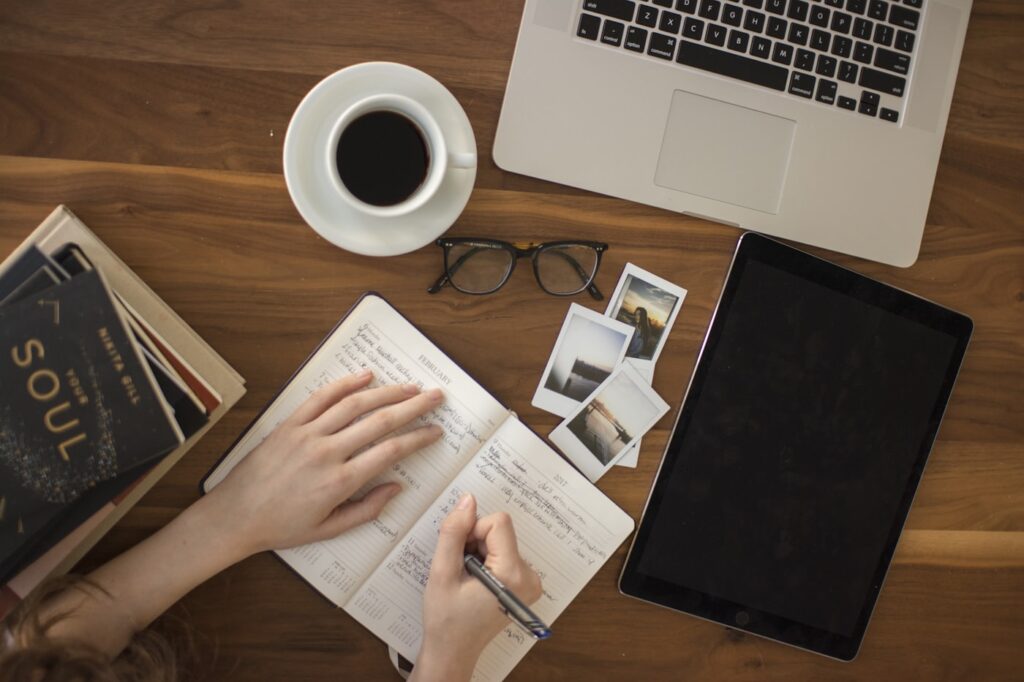 Journaling and planning how to choose a blog niche, notebook and laptop with coffee on a desk