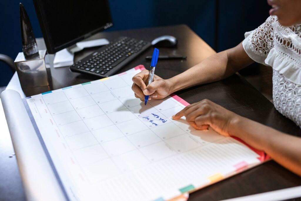 Woman writing into a monthly wall calendar at her desk