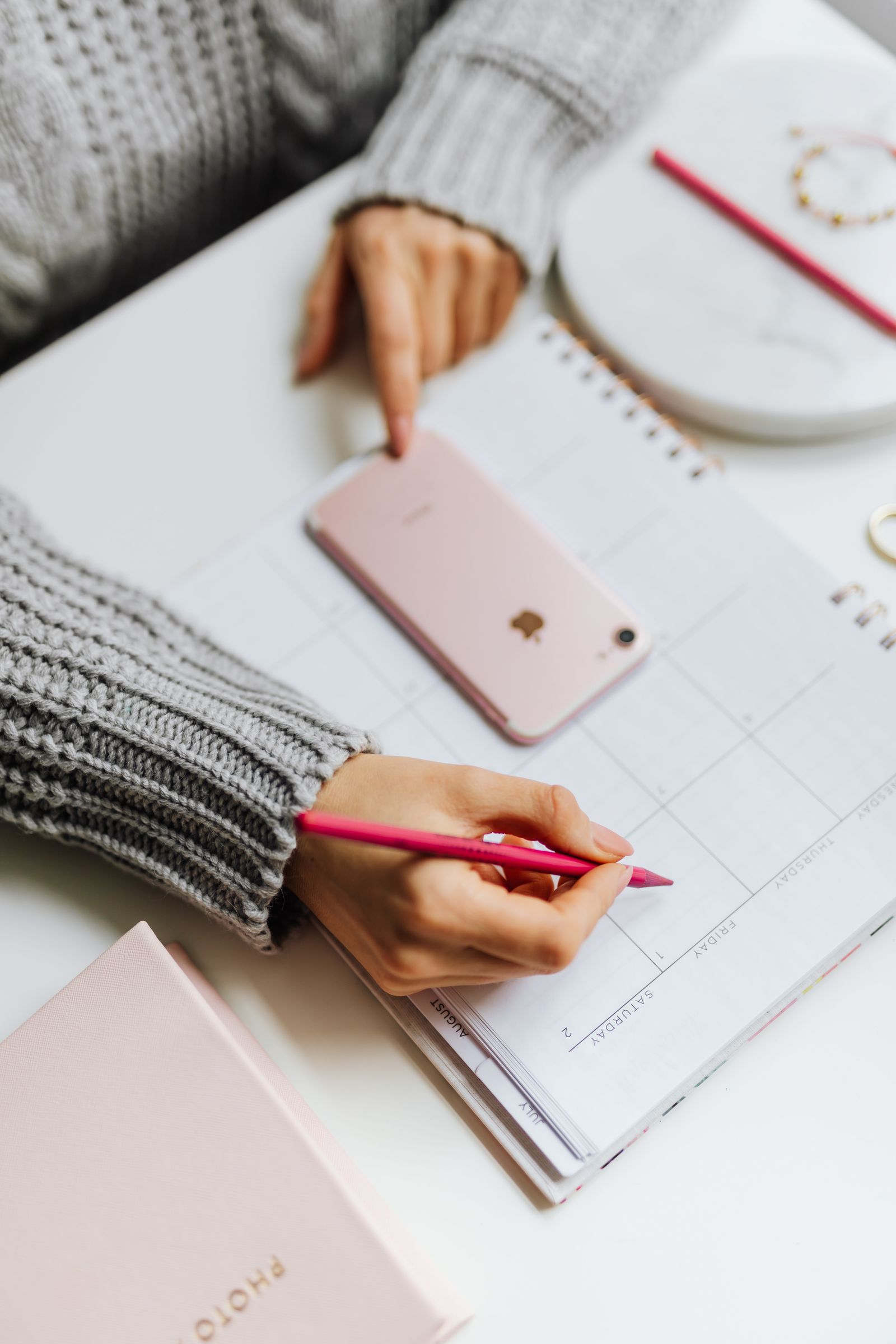 Person marking a specific date on a paper planner next to a phone