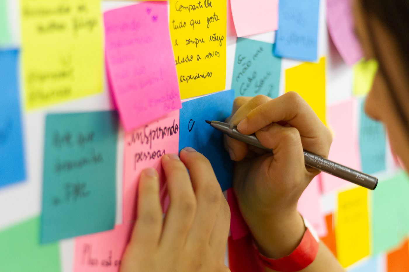 Close-up of hands writing ideas on colorful sticky notes while brainstorming blog topics
