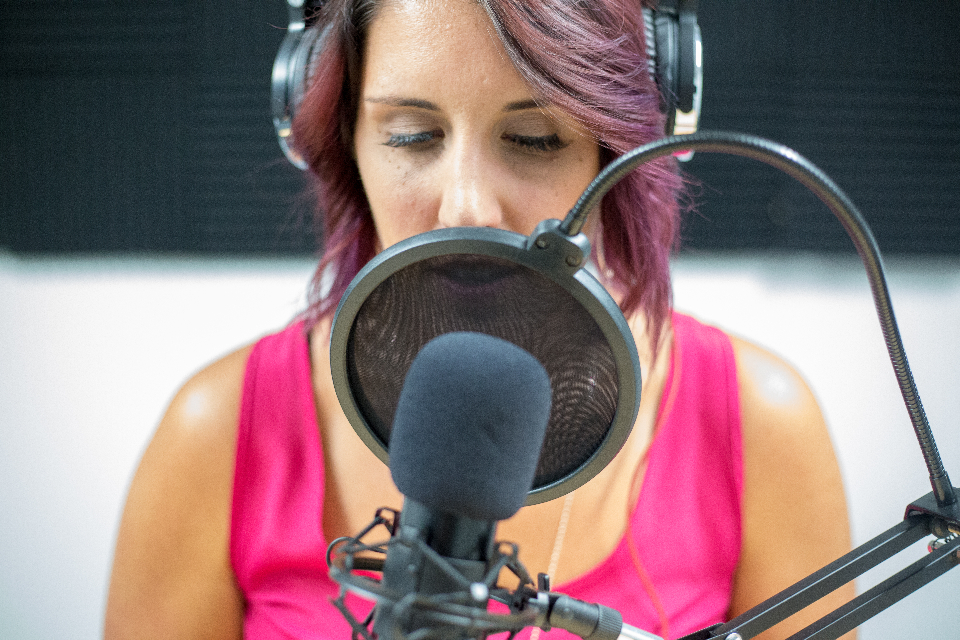 Podcast host speaking into a studio microphone with a pop filter during a recording session