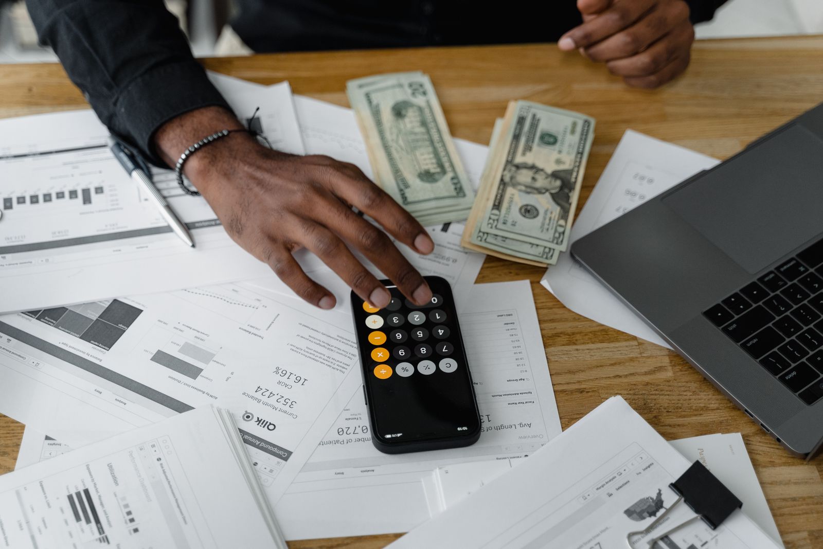 Close-up of a hand using a calculator next to financial paperwork